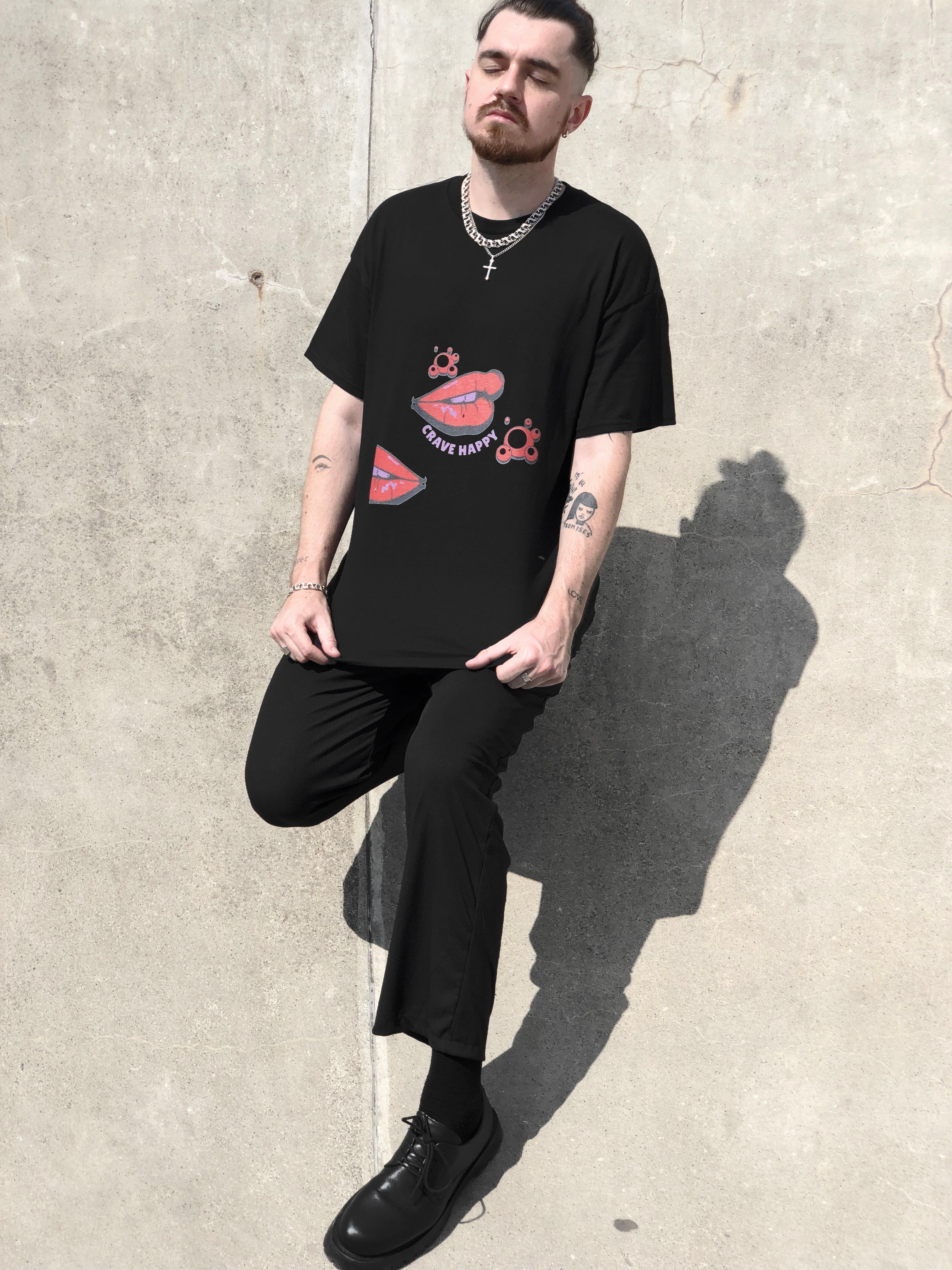 Person wearing a black t-shirt with graphic design against a concrete wall.